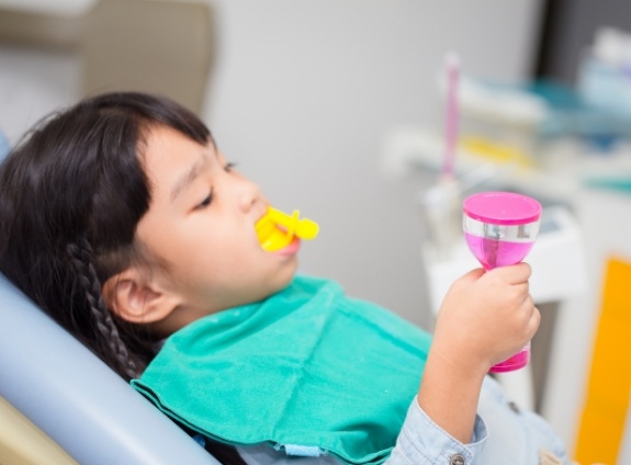 Young girl in dental chair with fluoride trays on her teeth