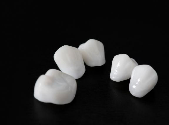 Five white dental crowns against black background