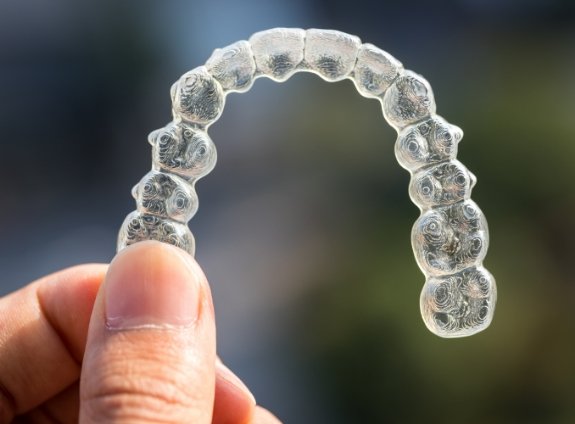 Hand holding an Invisalign clear aligner