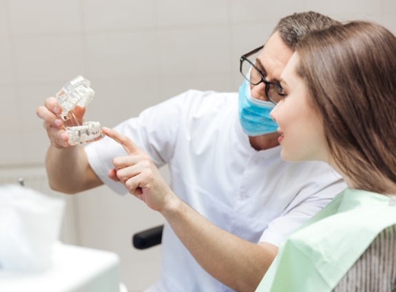 Dentist showing a dental implant model to a patient