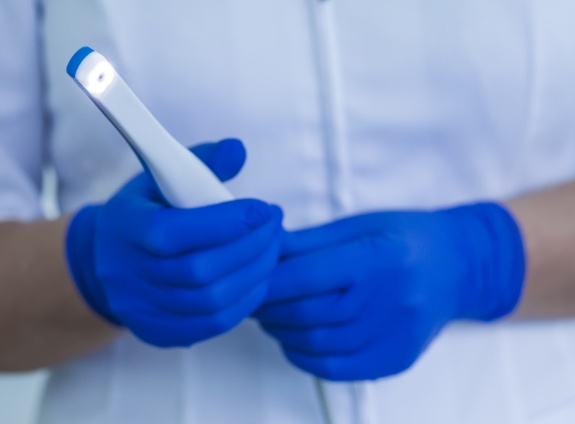 Dental team member holding a thin white intraoral camera