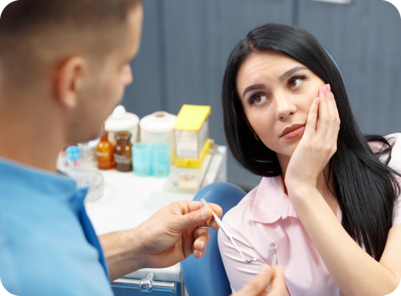 Woman in dental chair holding her cheek in pain