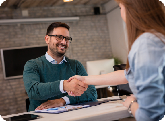 Man shaking hands with person sitting across desk