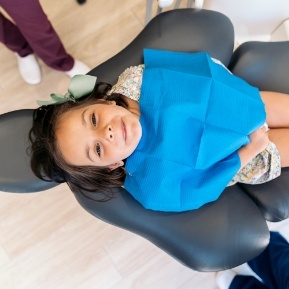 Young girl sitting in dental chair looking up