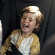 Laughing young boy sitting in backseat of car