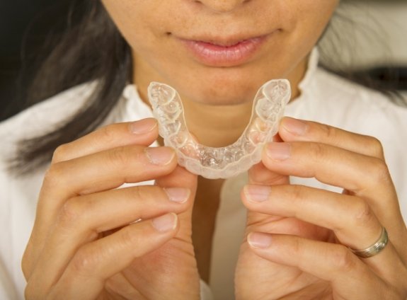 Person holding Invisalign tray near their mouth