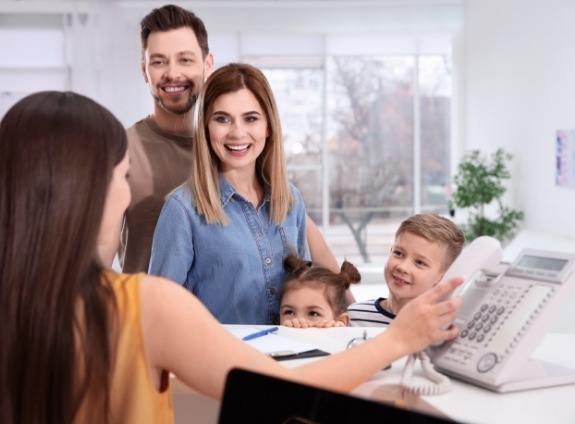 Family of four at dental office front desk