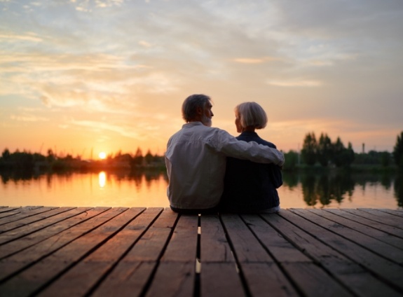 Man and woman sitting on a dock together at sunset