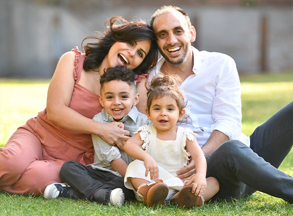 Doctor Ramtin sitting in grass with his wife and two children