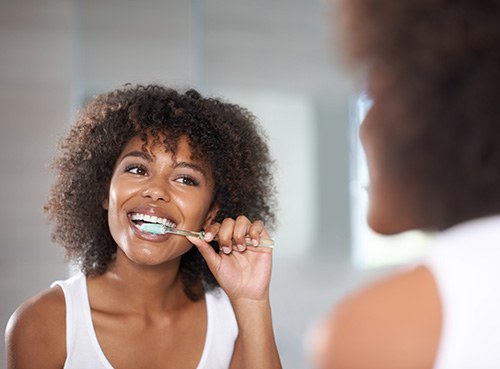 Woman smiling while brushing her teeth