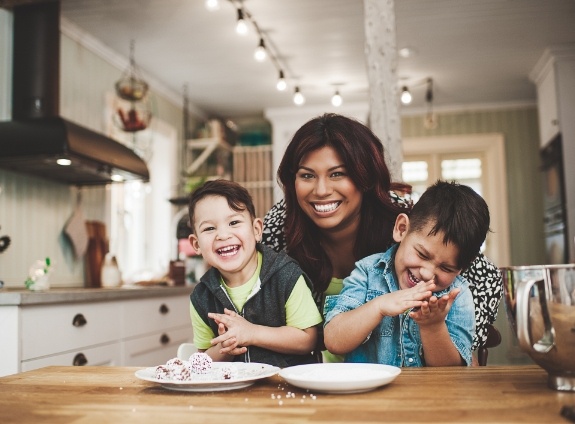 Mother and two sons smiling at kitchen table