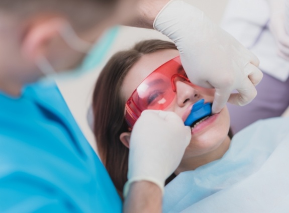 Young woman in dental chair with fluoride trays on her teeth