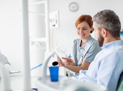 Dentist smiling while reviewing information with patient on tablet